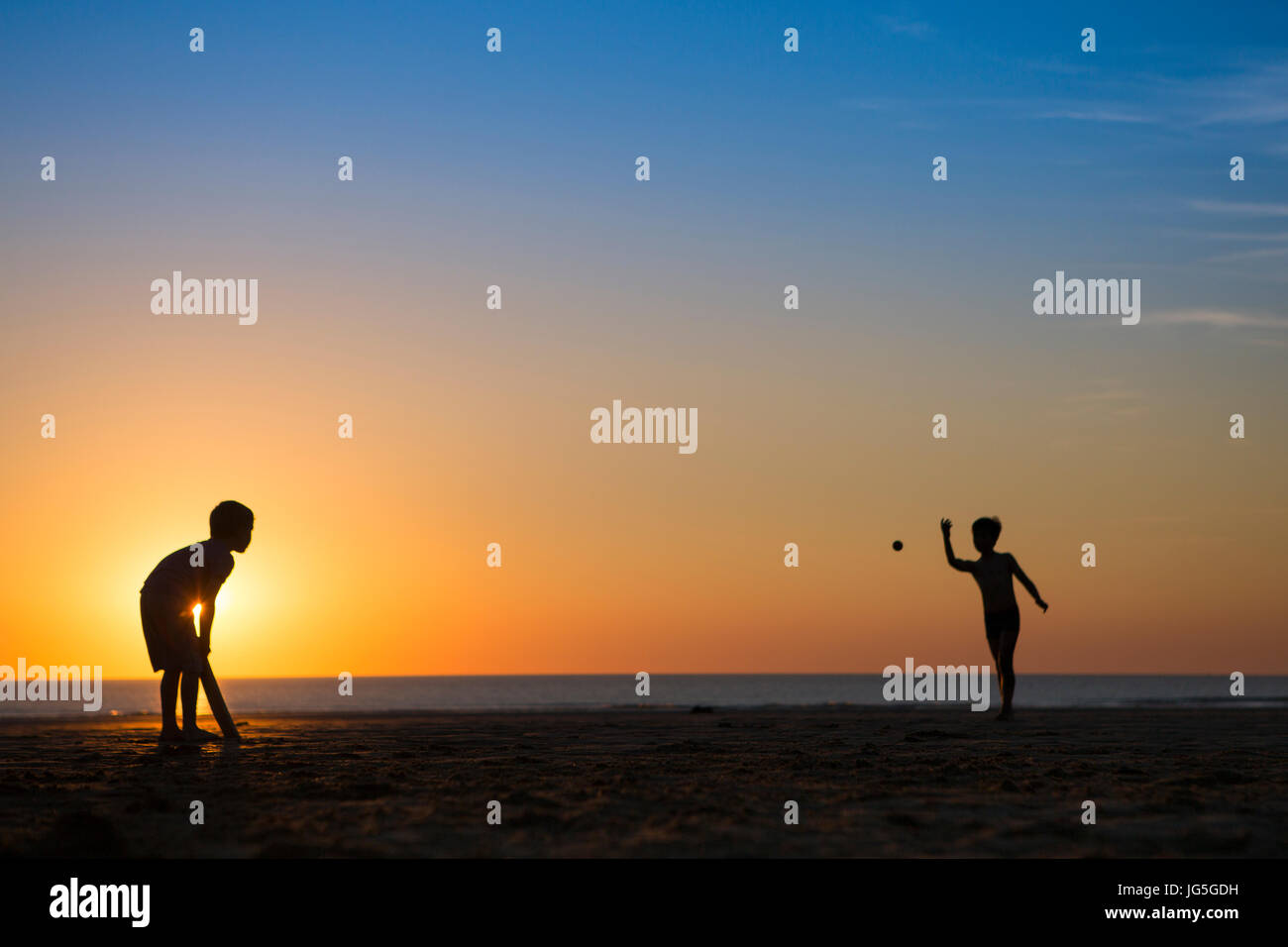 Due ragazzi giocare a cricket sulla spiaggia al tramonto, DEVON REGNO UNITO Foto Stock