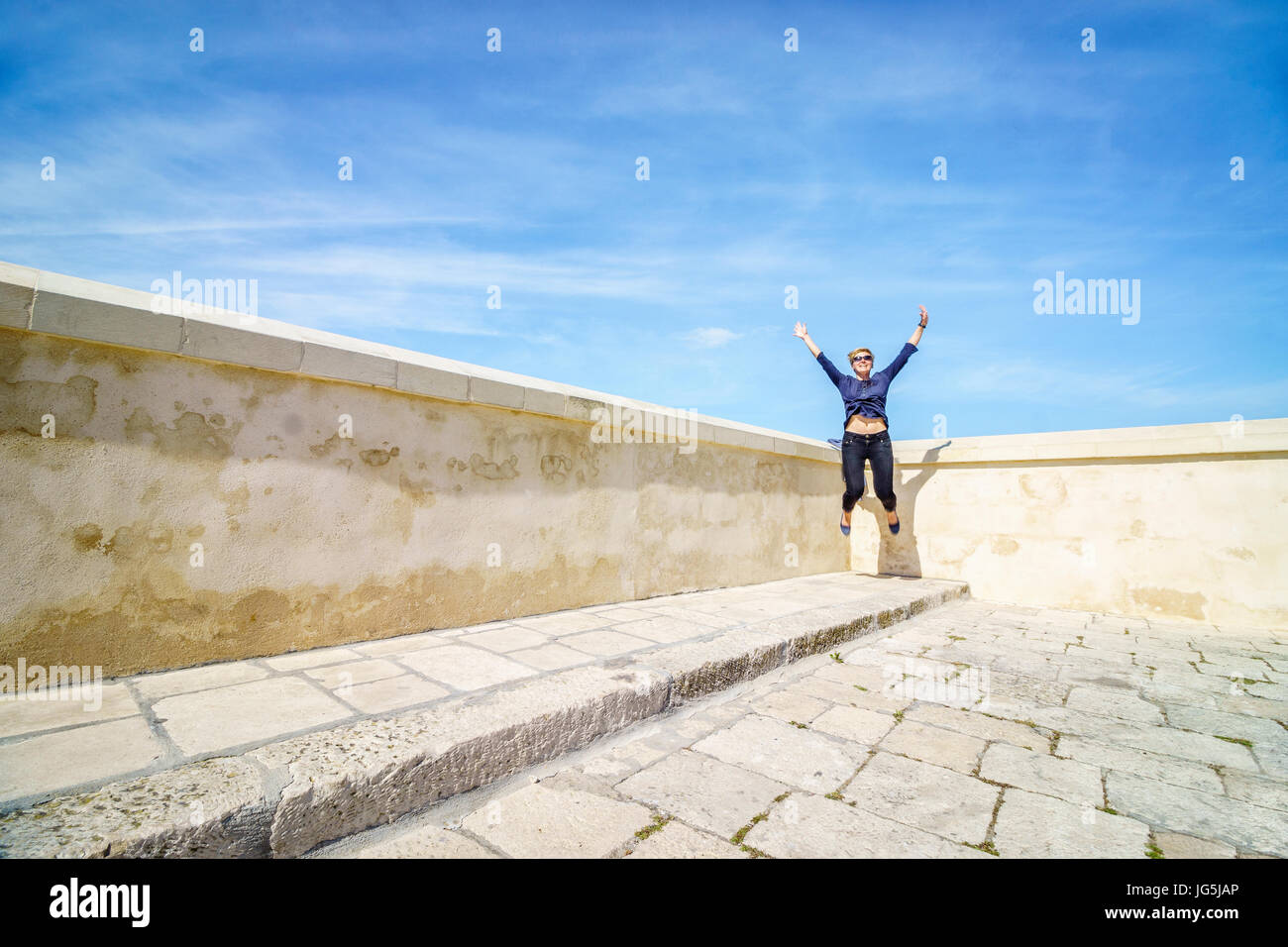 Donna felice di saltare in un angolo della terrazza, Italia Foto Stock