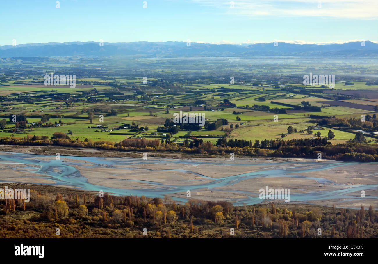 Canterbury Plains e fiume Waimakariri vista aerea come la nebbia cancella su una mattina autunnale, Nuova Zelanda. Sullo sfondo sono le Alpi del Sud. Foto Stock