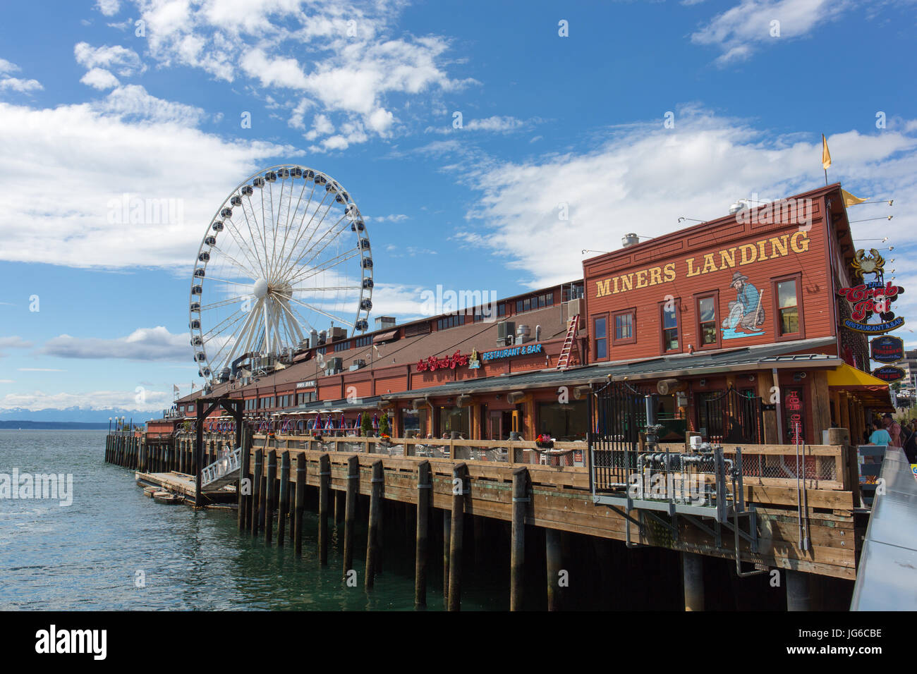 I minatori sbarco (pier 57) con il Seattle grande ruota (ruota panoramica Ferris) e le montagne olimpiche in background - Seattle, Washington Foto Stock