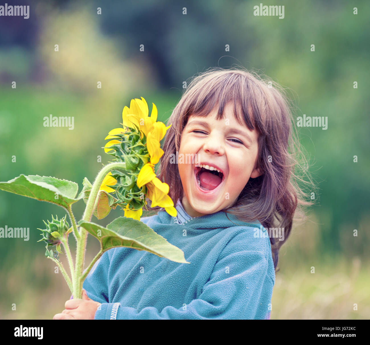 Felice di ridere bambina con un girasole all'aperto Foto Stock