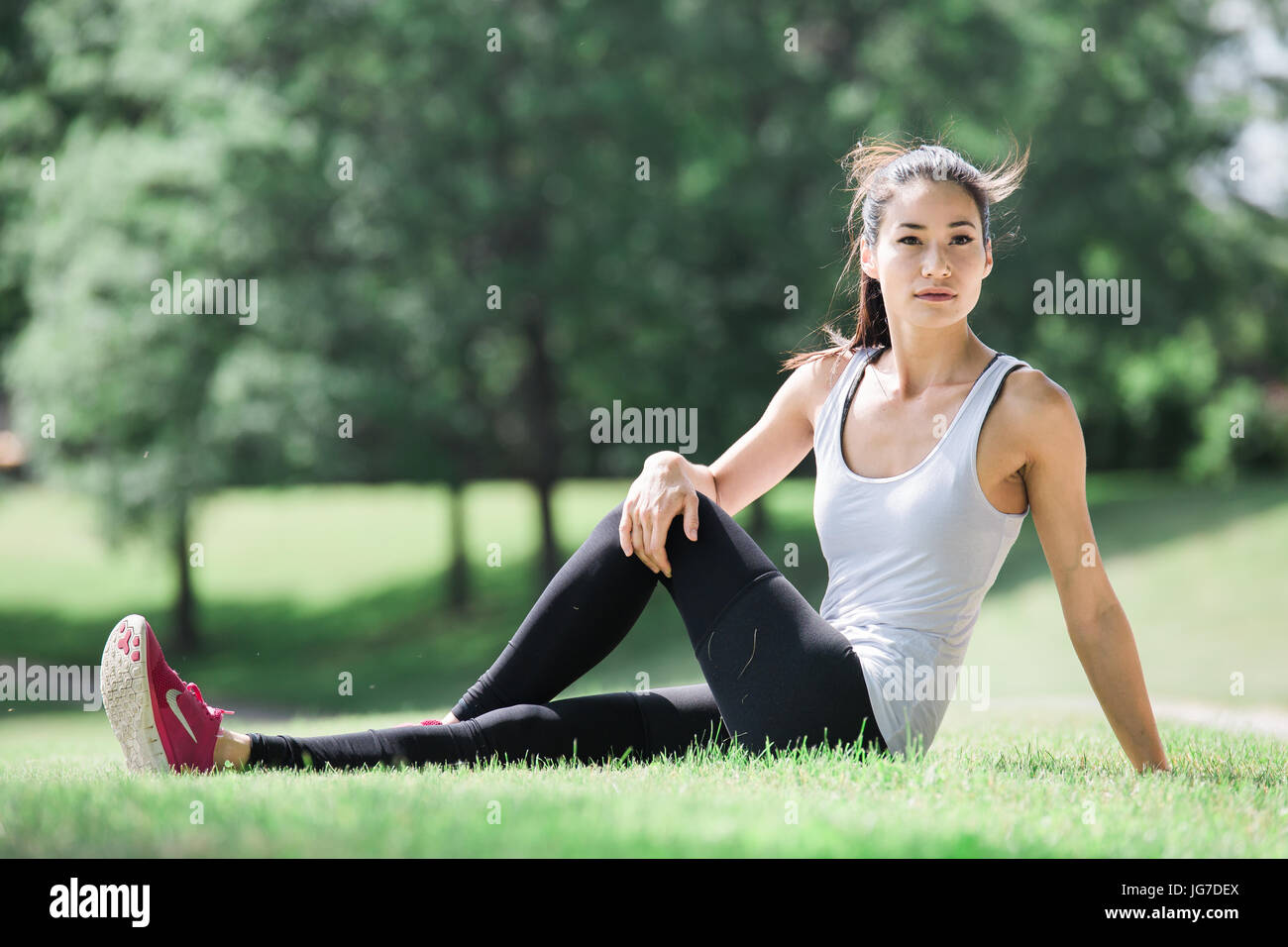 Una giovane e bella donna asiatica stretching, esercizio e fare yoga outdoor in un parco Foto Stock
