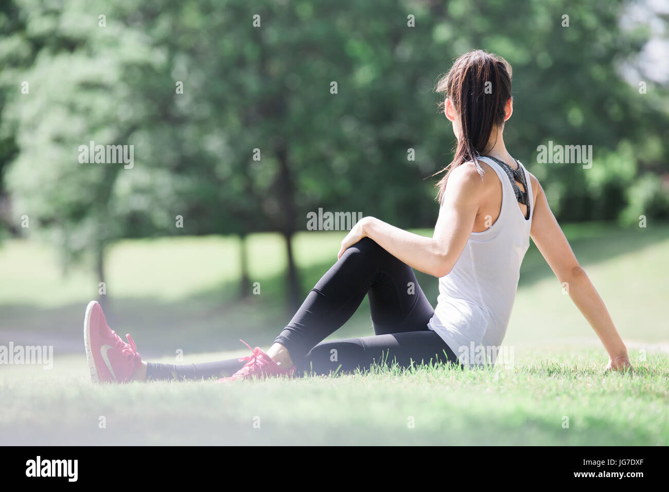 Una giovane e bella donna asiatica stretching, esercizio e fare yoga outdoor in un parco Foto Stock