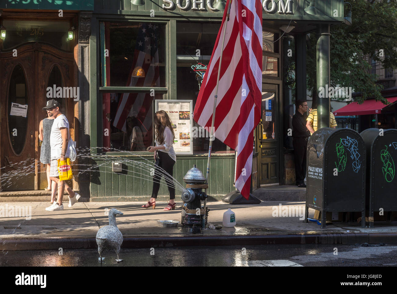 New York, NY, STATI UNITI D'AMERICA. 4 Luglio, 2017. Su Spring Street nel quartiere di Soho, alcuni newyorkesi hanno celebrato il Giorno di Indipendenza con un enorme bandiera americana, un idrante aperto e un falso credito d'anatra: Stacy Rosenstock Walsh/Alamy Live News Foto Stock