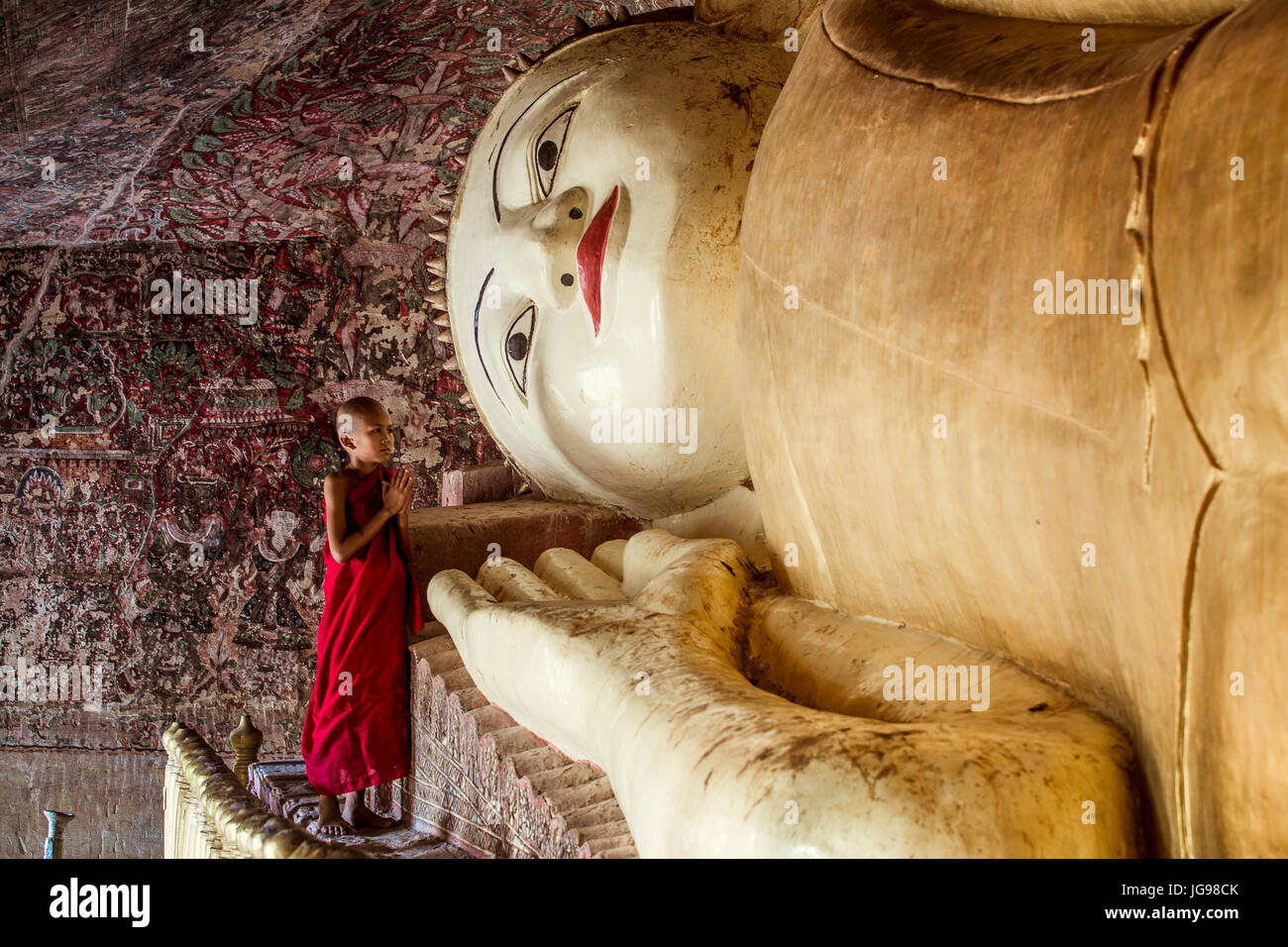 Buddista monaco novizio / little monk / giovane monaco culto bella grande Buddha reclinato statua nella grotta Phowintaung Monywa Myanmar Foto Stock