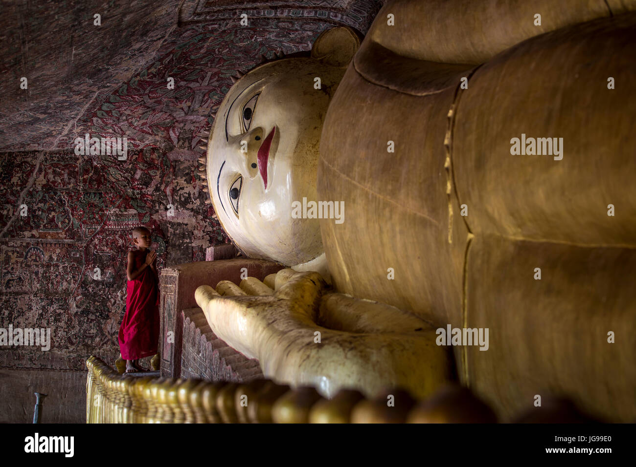 Buddista monaco novizio / little monk / giovane monaco culto bella grande Buddha reclinato statua nella grotta Phowintaung Monywa Myanmar Foto Stock
