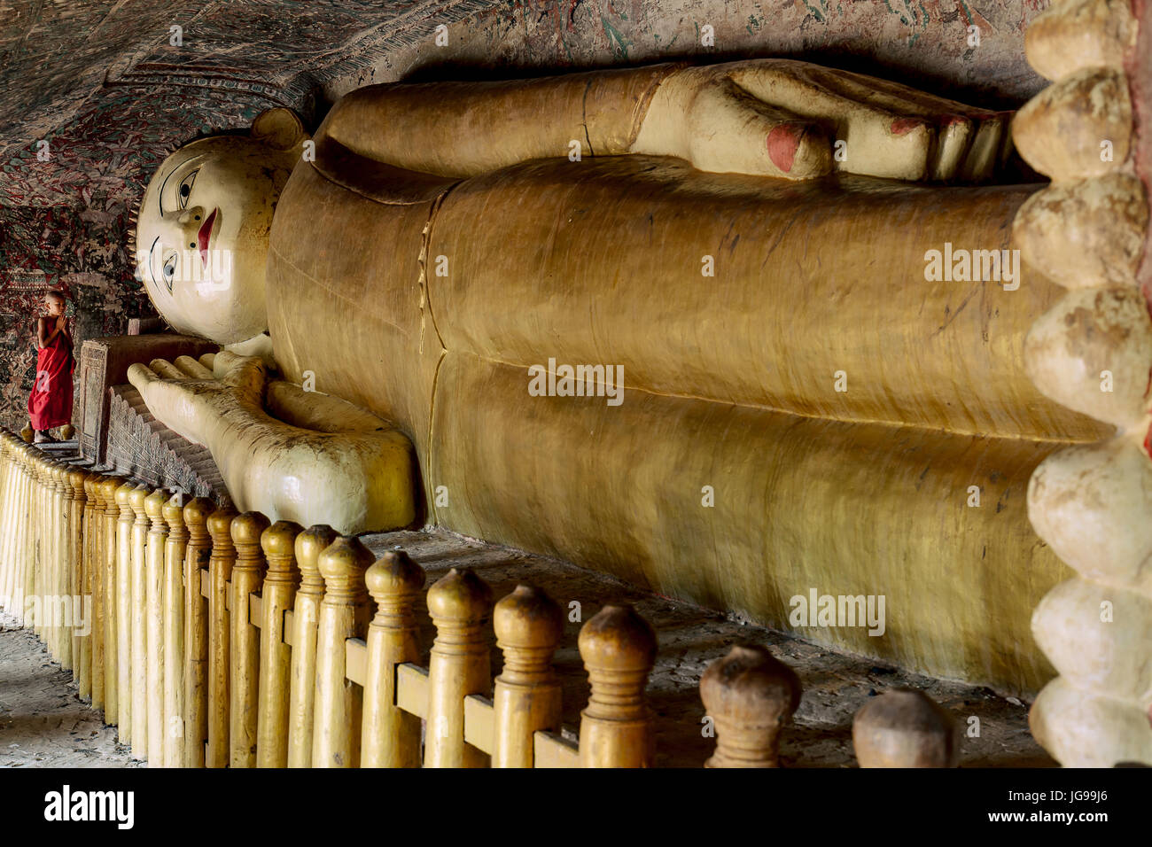 Buddista monaco novizio / little monk / giovane monaco culto bella grande Buddha reclinato statua nella grotta Phowintaung Monywa Myanmar Foto Stock