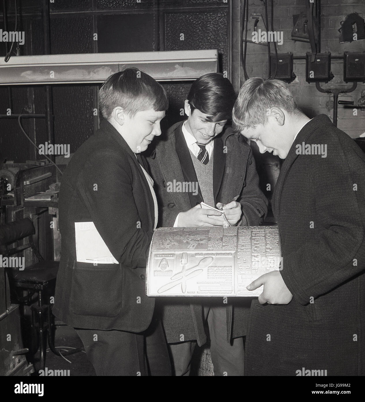 Anni Sessanta, tre ragazzi studiano una lastra di stampa in metallo in una visita alle presse per la stampa del South East London e del quotidiano Kentish Mercury, Inghilterra, Regno Unito. Foto Stock