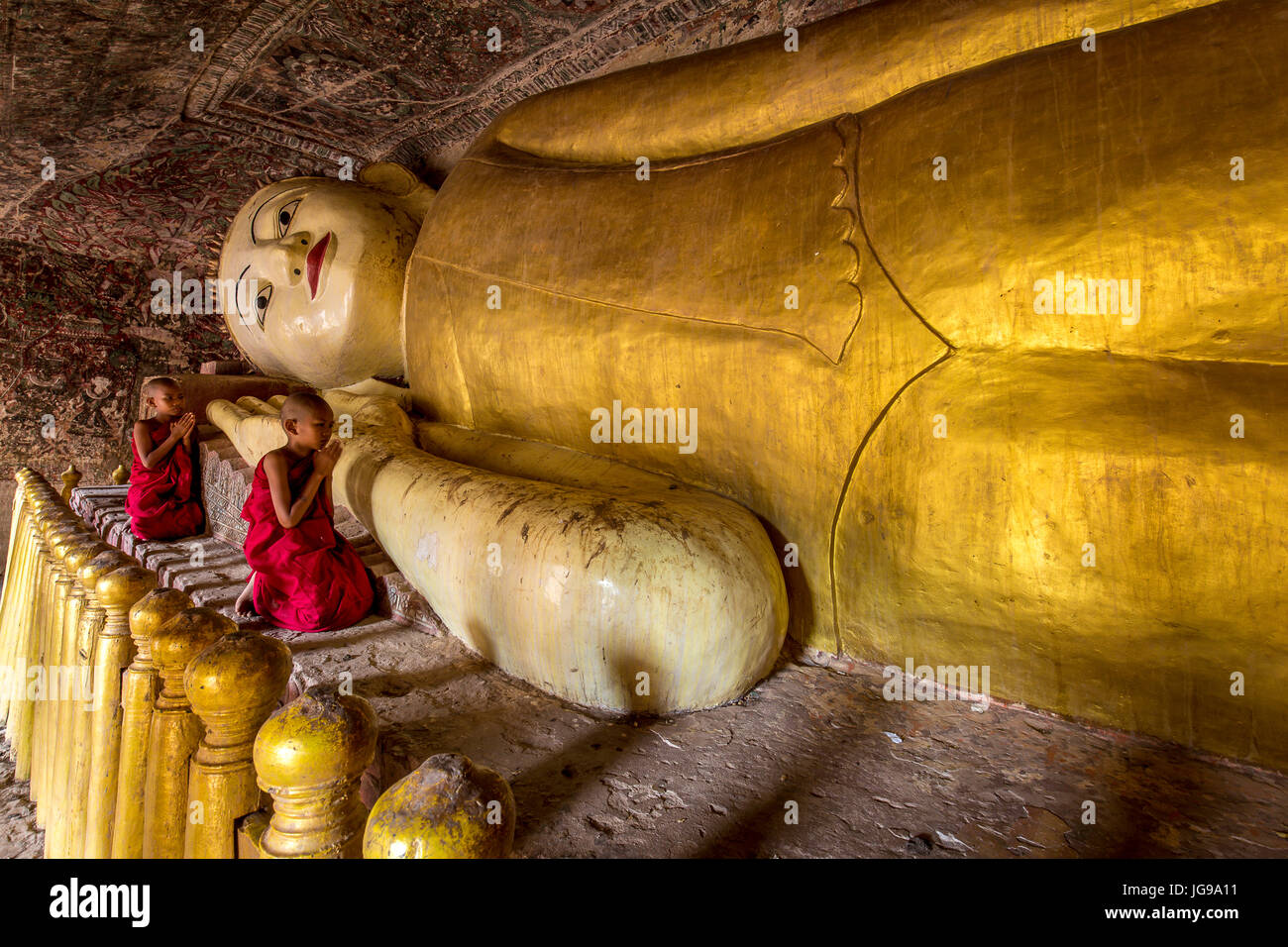 Buddista monaco novizio / little monk / giovane monaco culto bella grande Buddha reclinato statua nella grotta Phowintaung Monywa Myanmar Foto Stock