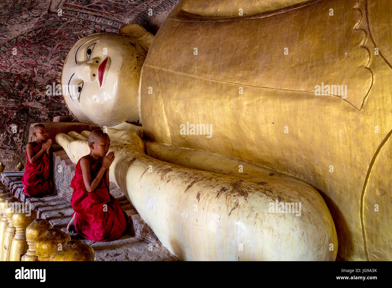 Buddista monaco novizio / little monk / giovane monaco culto bella grande Buddha reclinato statua nella grotta Phowintaung Monywa Myanmar Foto Stock