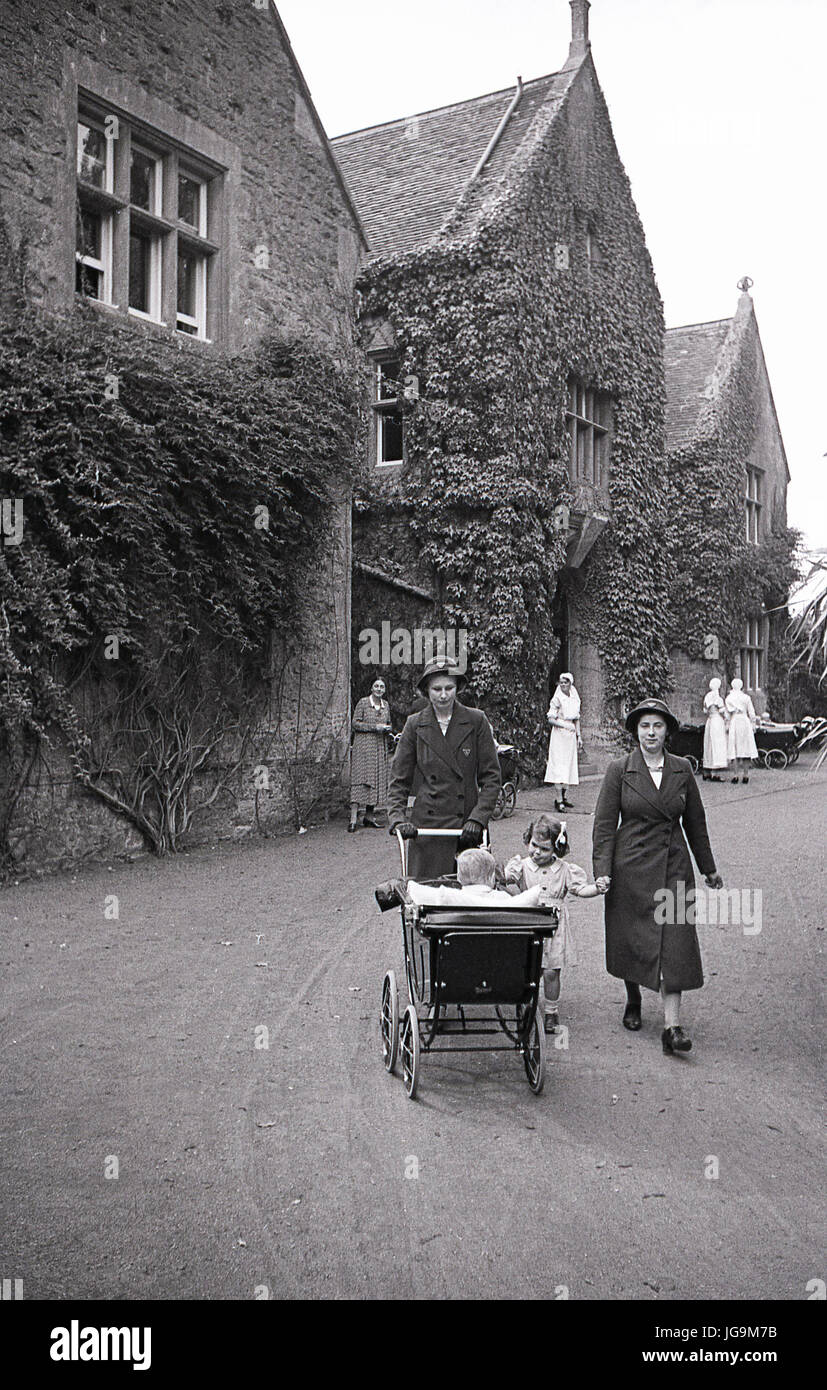 Negli anni Quaranta, in Inghilterra, in tempo di guerra, immagine mostra la parte esterna di Stanstead Hall, casa di lady Butler (Sydney Courtauld) moglie del maggiordomo di Rab, politiican conservatore e ministro, due infermieri a piedi una carrozzina nel vialetto con bambini evacuati da Hampstead garden sobborghi di Londra. Foto Stock Negli anni Quaranta, in Inghilterra, in tempo di guerra, immagine mostra la parte esterna di Stanstead Hall, casa di lady Butler (Sydney Courtauld) moglie del maggiordomo di Rab, politiican conservatore e ministro, due infermieri a piedi una carrozzina nel vialetto con bambini evacuati da Hampstead garden sobborghi di Londra. Foto Stock