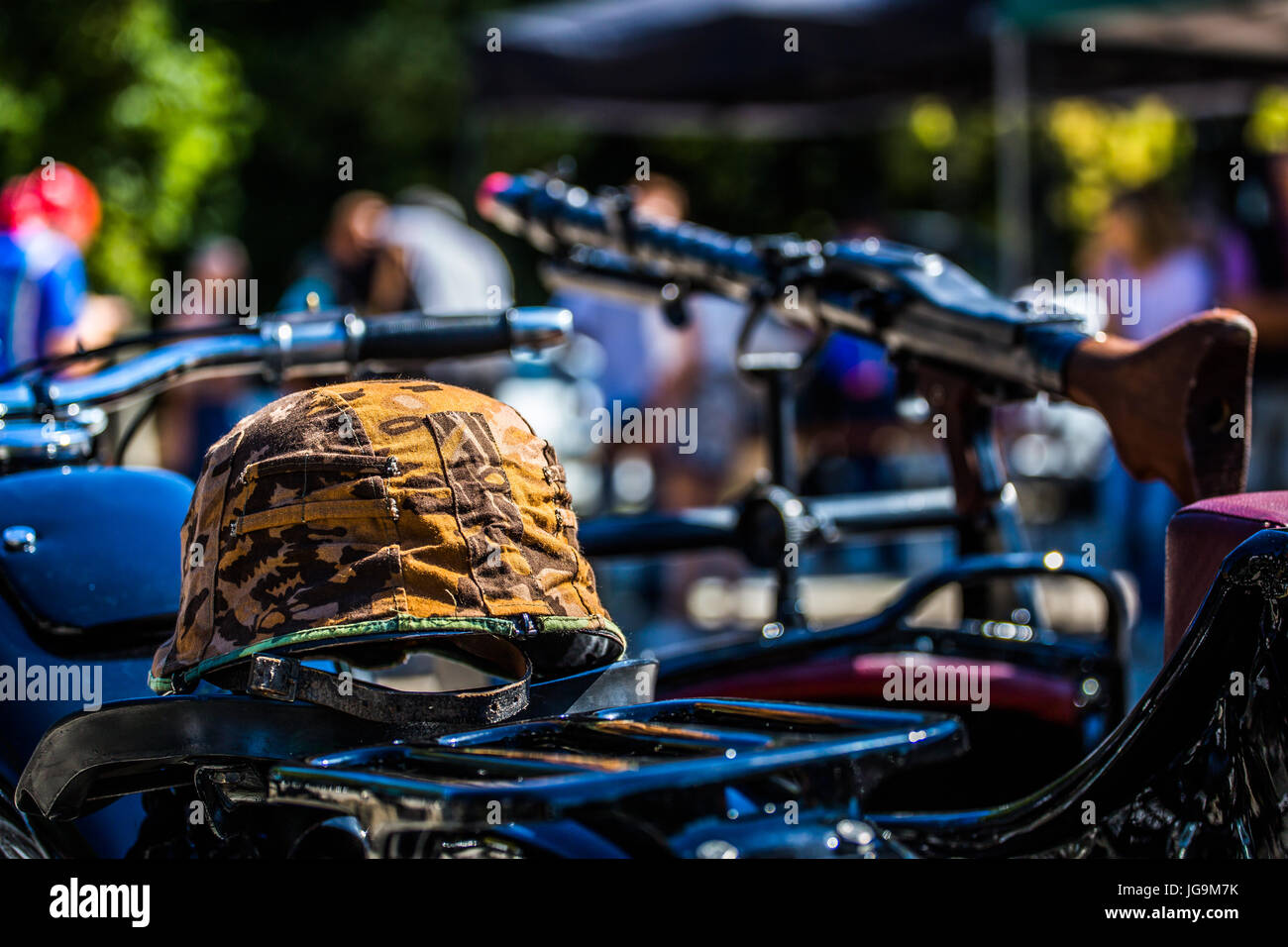 Cappello militare giacente su BMW R71 vecchia motocicletta dopo la ristrutturazione con un fucile (TOY) in background. Foto Stock