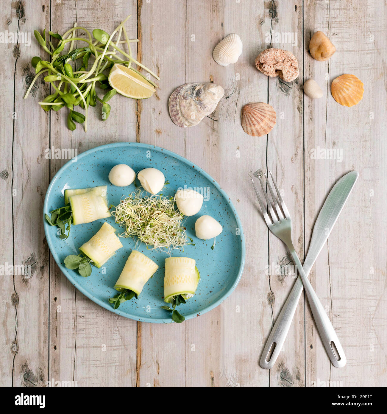 Involtini primavera con zucchine e mozzarella. Il cibo con micro verdi su sfondo di legno. Foto Stock