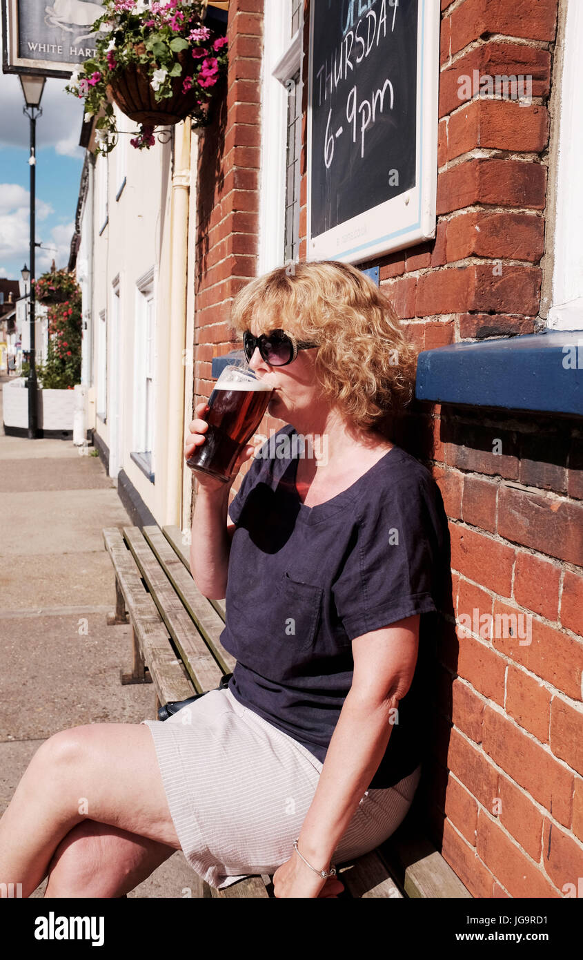 Aldeburgh Suffolk REGNO UNITO Giugno 2017 - Donna di bere una pinta di birra sul marciapiede esterno pub nelle calde giornate estive Foto Stock