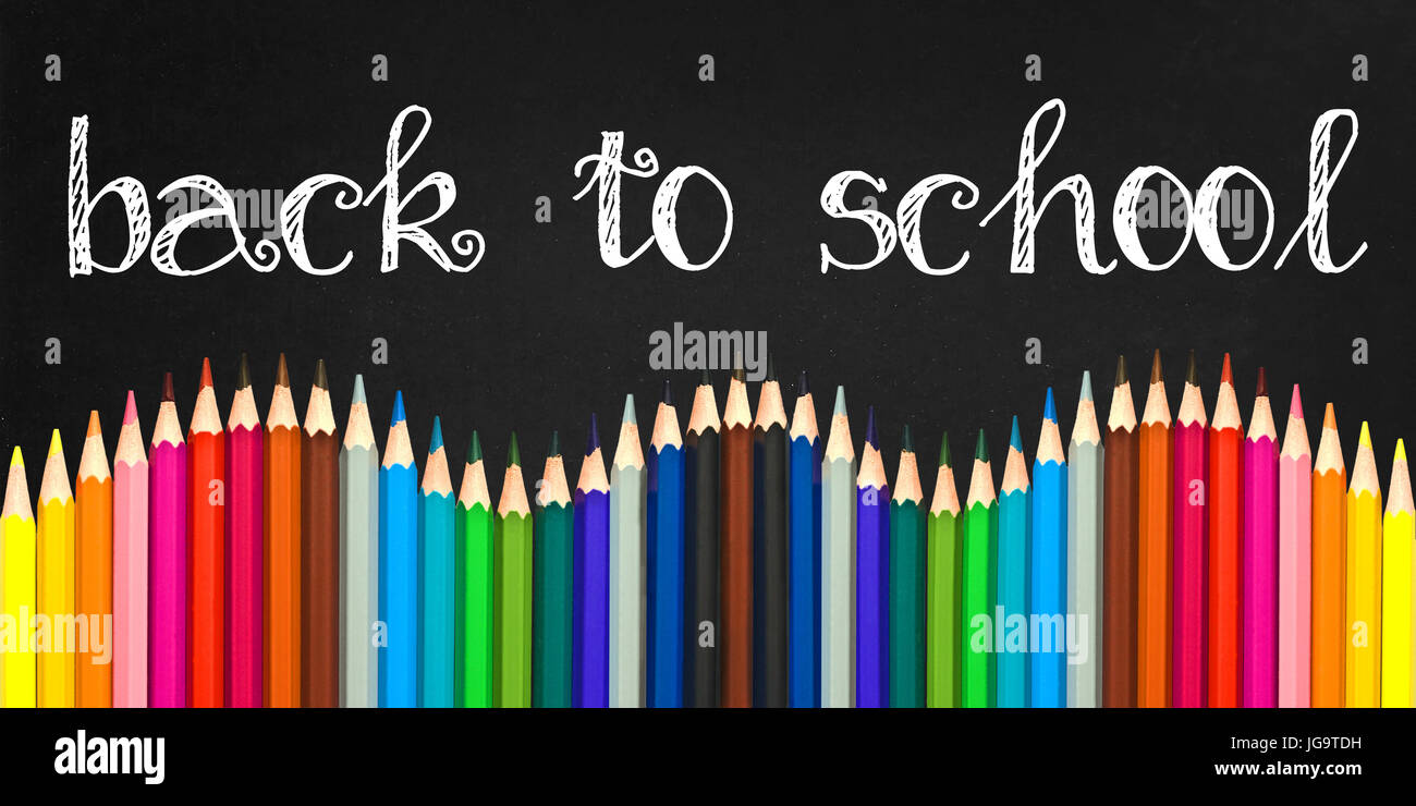 Si torna a scuola scritto su una scheda di colore nero lo sfondo con un onda di colorate matite in legno Foto Stock