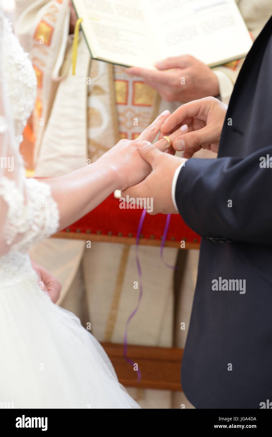 Una sposa sposo stanno scambiando le loro fedi in chiesa, sacerdote azienda libro di nozze Foto Stock
