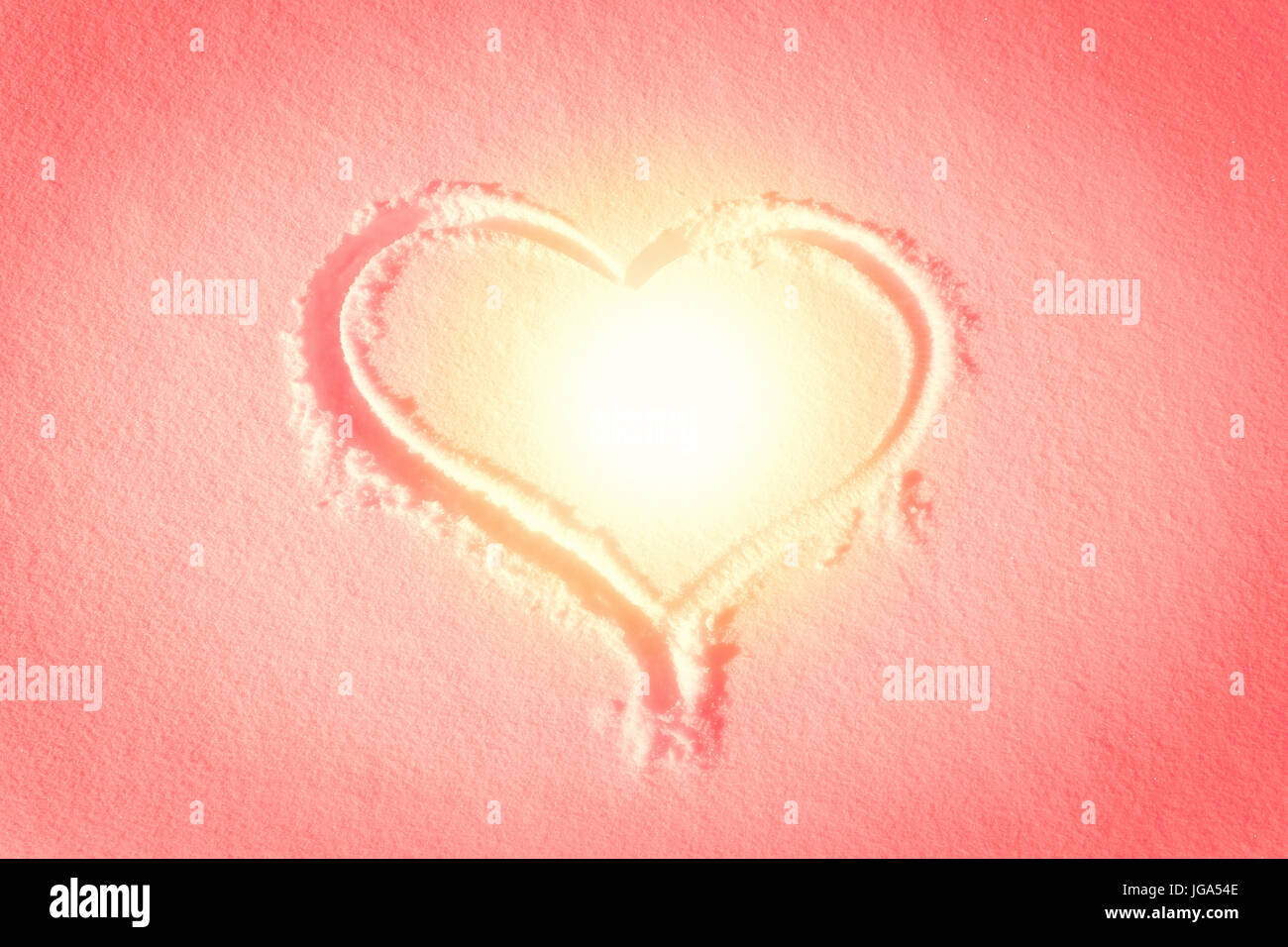 Forma di cuore disegnato nella neve, caldo tramonto colori di stile Foto Stock