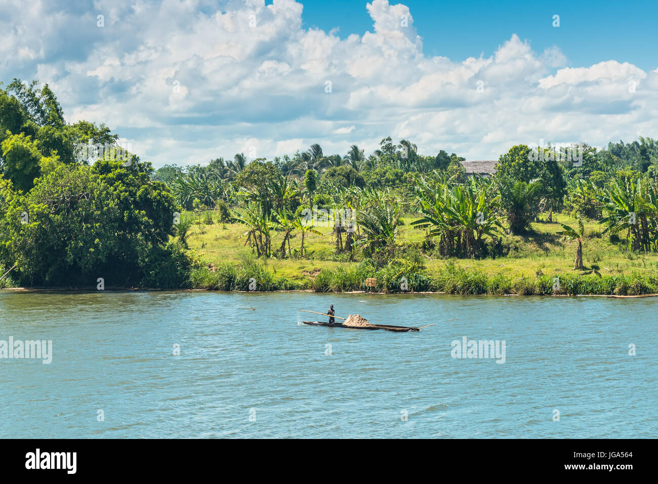 Ivoloina, Madagascar - Dicembre 22, 2015: campagna malgascio l uomo dal villaggio di trasporto da tradizionale a mano piroga imbarcazione in legno vicino al Foto Stock