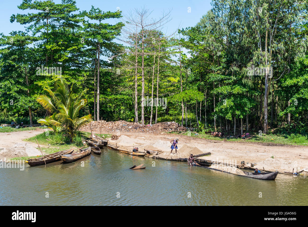 Ivoloina, Madagascar - Dicembre 22, 2015: campagna malgascio persone dal villaggio di sabbia di scarico da tradizionale a mano piroga barche di legno vicino Foto Stock