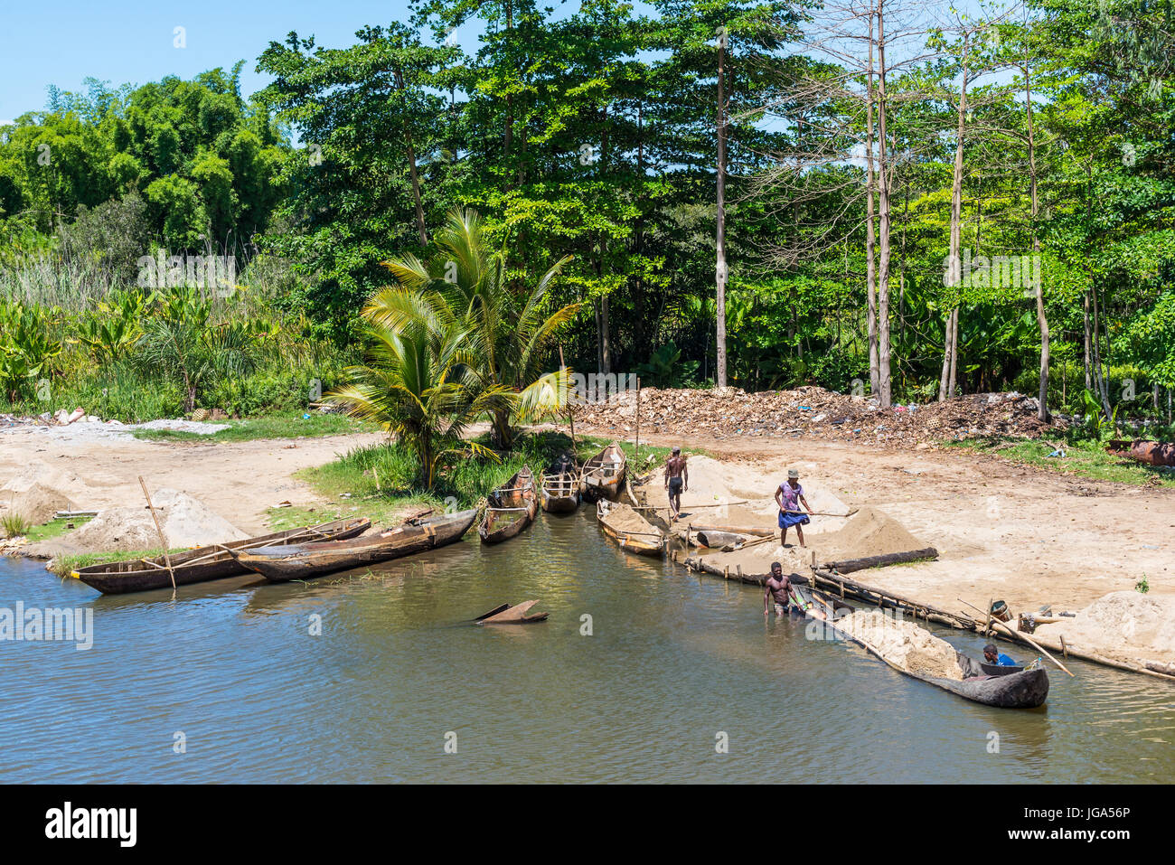 Ivoloina, Madagascar - Dicembre 22, 2015: campagna malgascio persone dal villaggio di sabbia di scarico da tradizionale a mano piroga barche di legno vicino Foto Stock