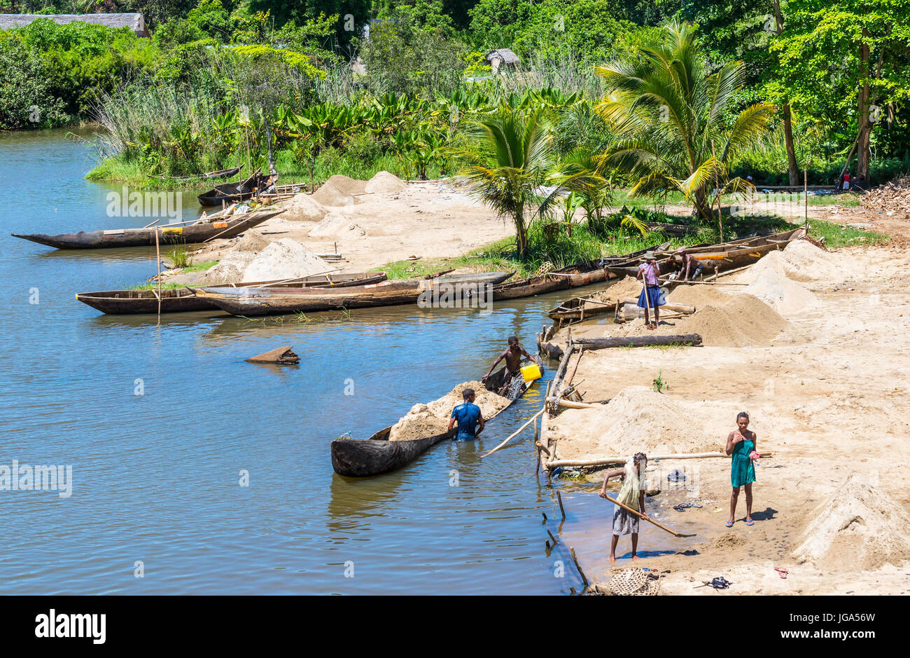Ivoloina, Madagascar - Dicembre 22, 2015: campagna malgascio persone dal villaggio di sabbia di scarico da tradizionale a mano piroga barche di legno vicino Foto Stock