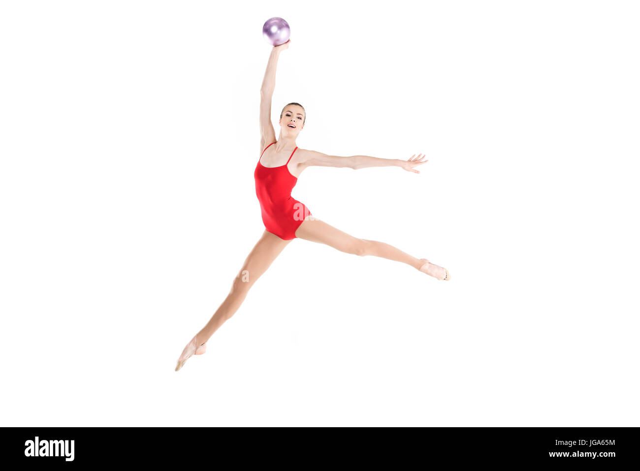 Giovane donna caucasica ginnasta ritmica jumping con sfera Foto Stock