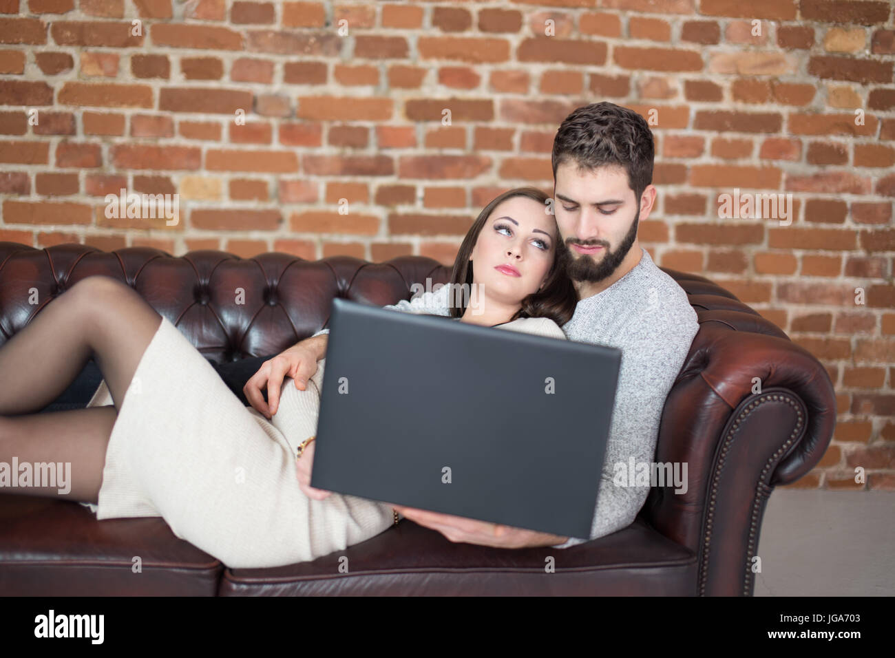Giovane uomo guardare fino a uomo sul divano con il computer portatile, fiducia Foto Stock