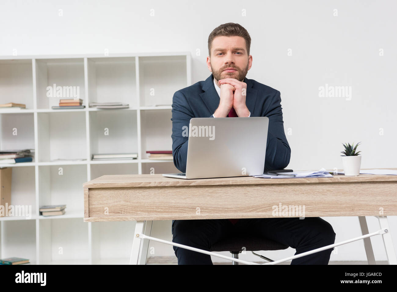 Imprenditore pensieroso seduta a tavola con il computer portatile in ufficio Foto Stock