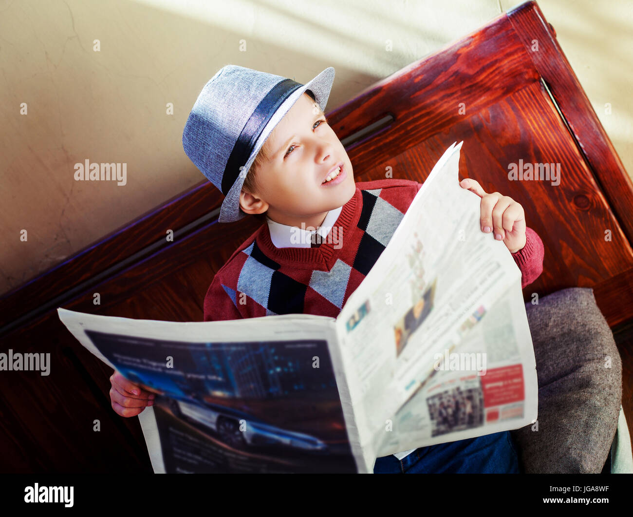 Felice ragazzo elegante con un giornale sul banco di lavoro Foto Stock