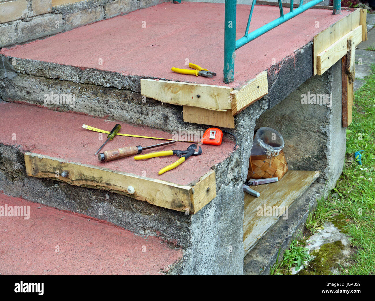 Semplice riparazione casalinga del distrutto portico di cemento in una povera casa rurale. Vecchi strumenti arrugginito giacciono sotto la pioggia. Collage panoramico da diverse foto Foto Stock