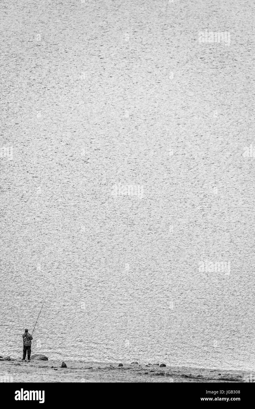 Il paesaggio del lago con il pescatore in piedi sulla riva Foto Stock