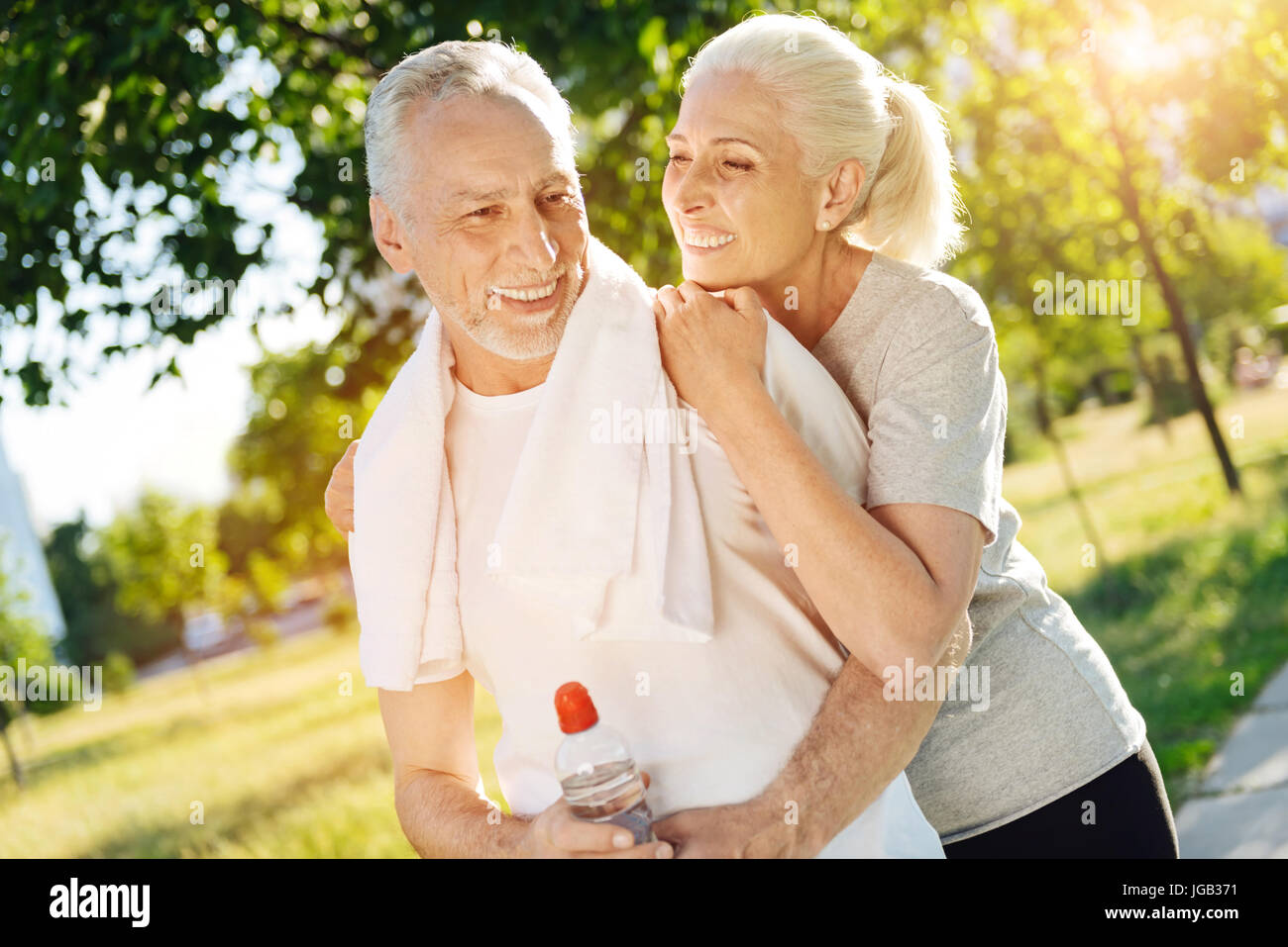 Positivo sorridente in pensione matura in appoggio nel parco dopo il jogging Foto Stock