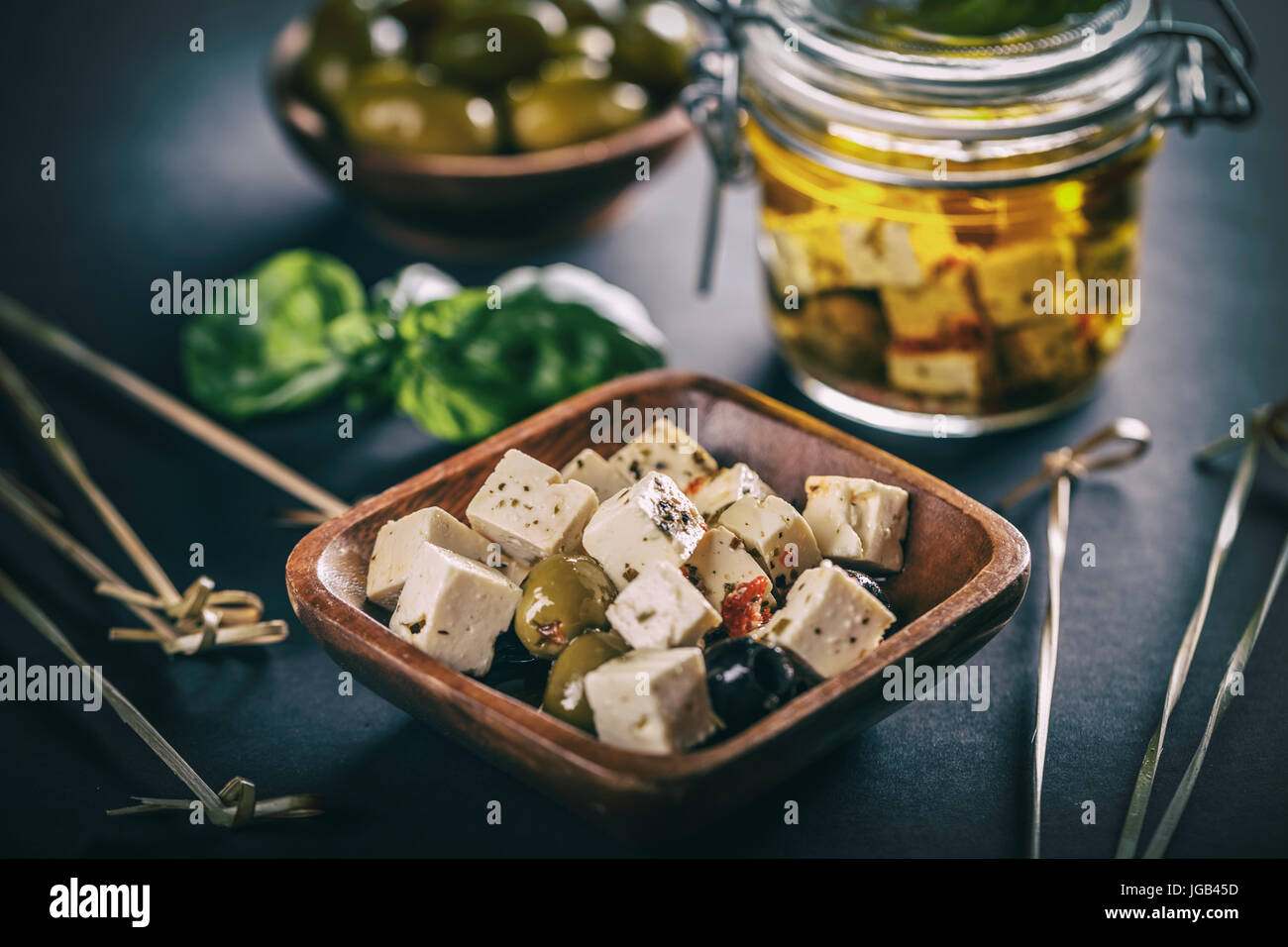 Cubetti di formaggio con semi di oliva in vaso di bambù Foto Stock