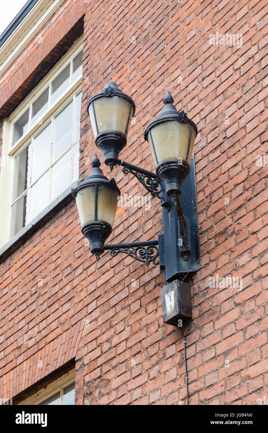 In vecchio stile trio di lampioni attaccata alla parete di edificio in mattoni rossi in Tamworth, Staffordshire Foto Stock