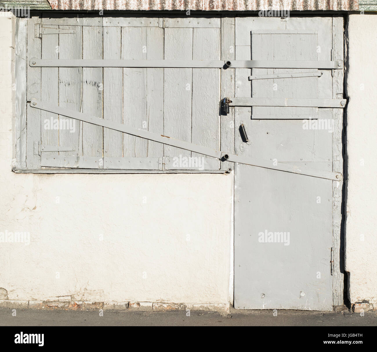 Texture Foto di vecchie porte in legno e finestre con inserti in metallo e una cerniera di bloccaggio del granaio. Le porte e le finestre sono dipinte in grigio Foto Stock