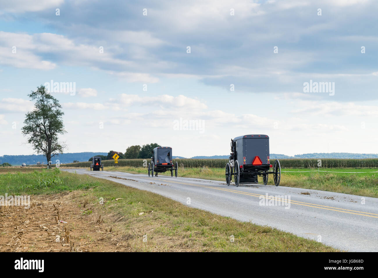 Tre carrozze amish lungo una strada rurale in Lancaster County, Pennsylvania Foto Stock