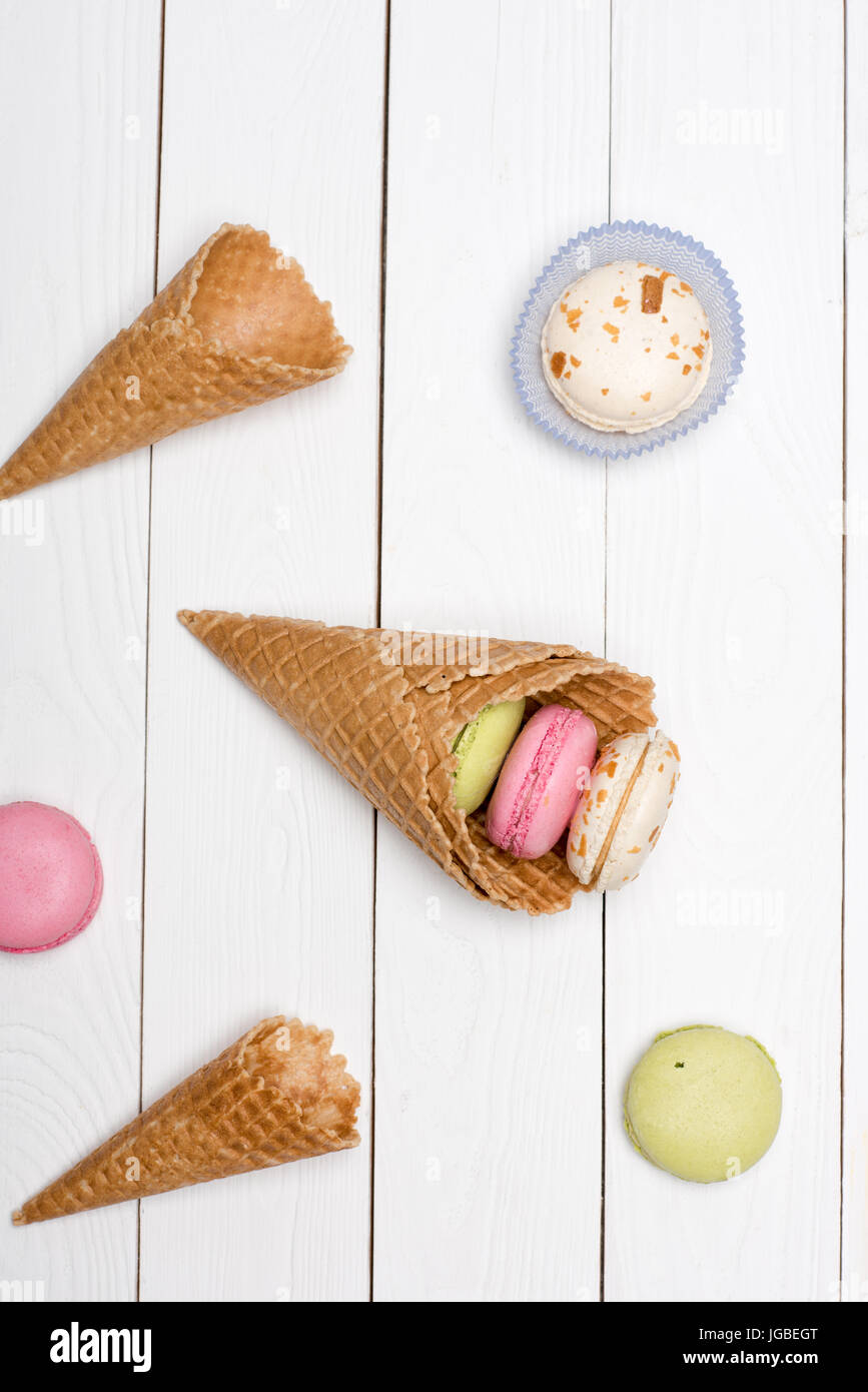 Gruppo di coni di cialda e colorati macarons. macarons sullo sfondo Foto Stock