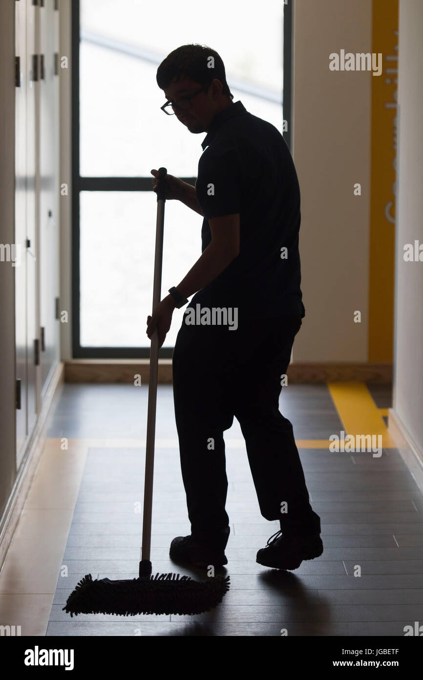 Un non identificabili, stagliano cleaner al lavoro la pulizia del pavimento in un salario minimo lavoro. Foto Stock