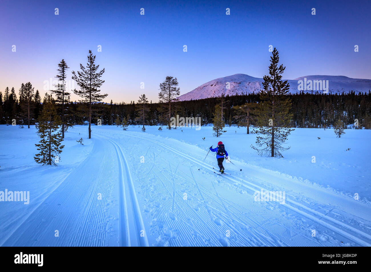 Bambino sci cross country dopo il tramonto, con meravigliosa luce artica sopra il Monte Trysilfjellet in Norvegia Foto Stock