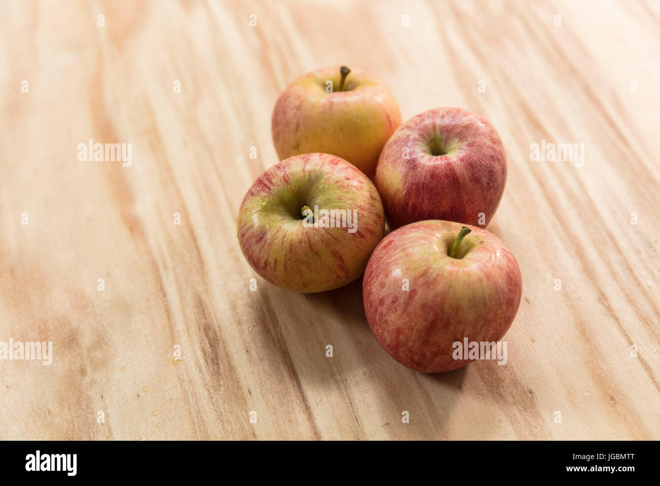 Quattro le mele su una superficie di legno. Pink Lady varietà Foto Stock