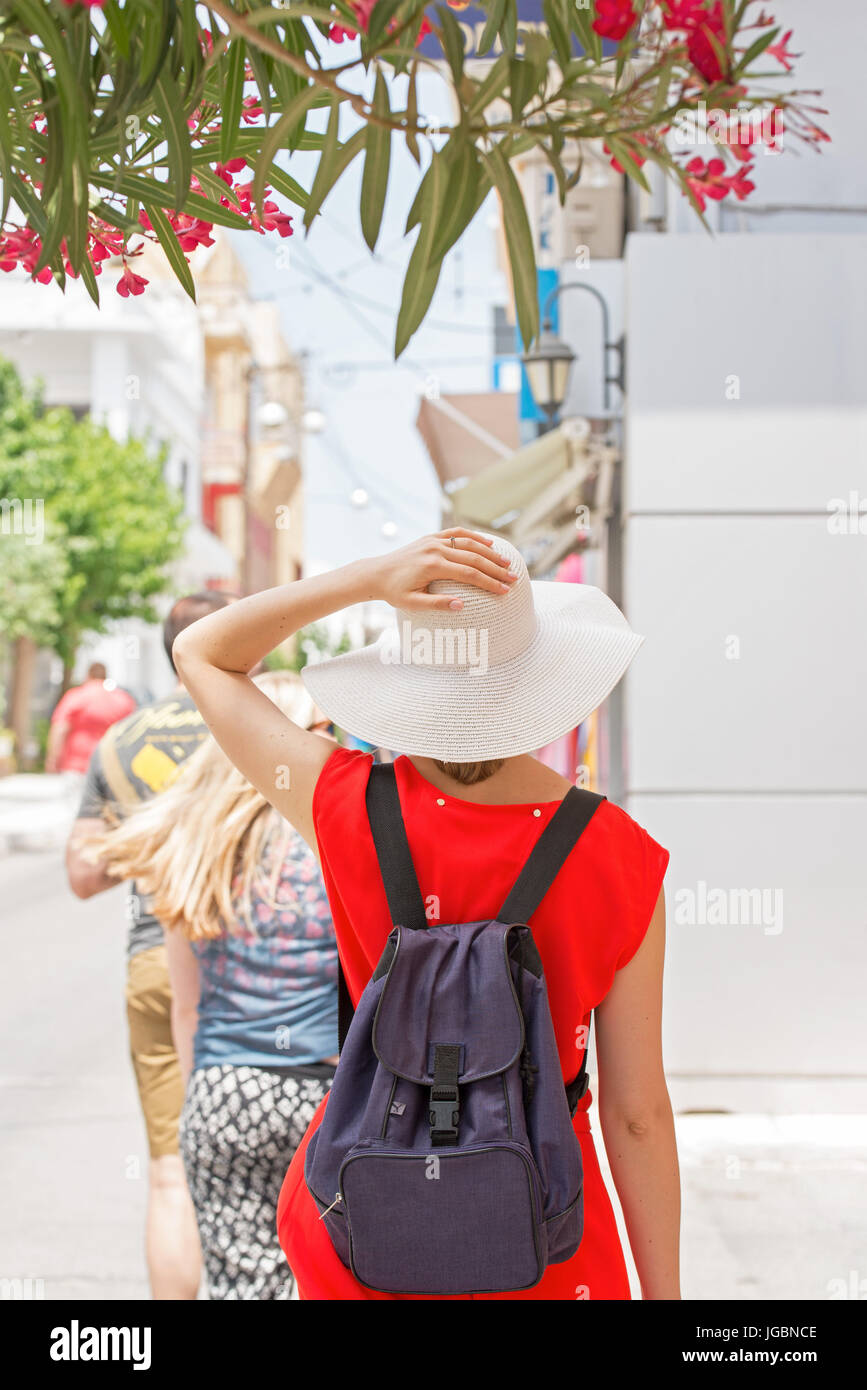 Donna in abito rosso, white hat zaino e passeggiate in città Foto Stock