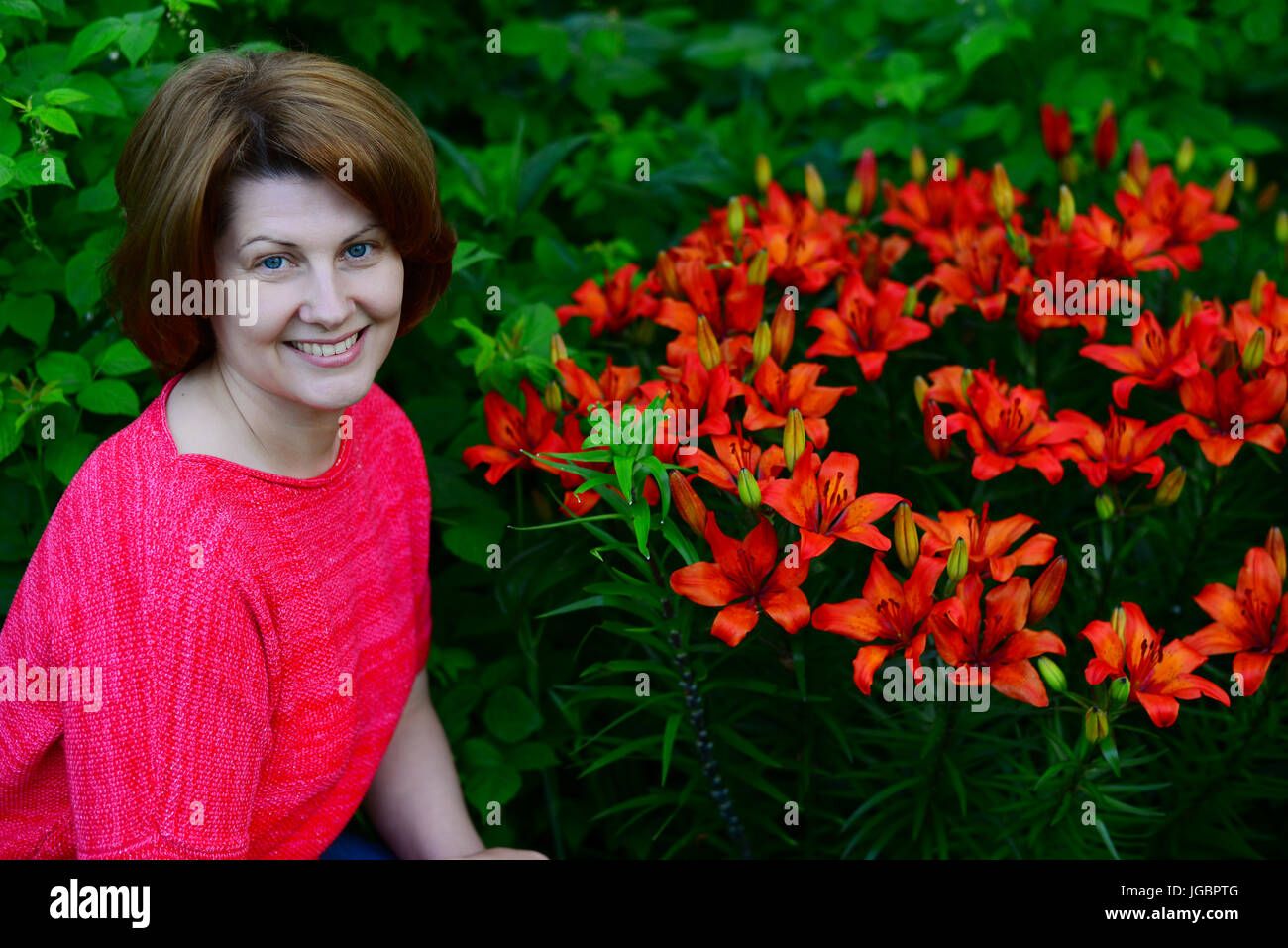 Donna vicino al letto di fiori con gigli arancione Foto Stock