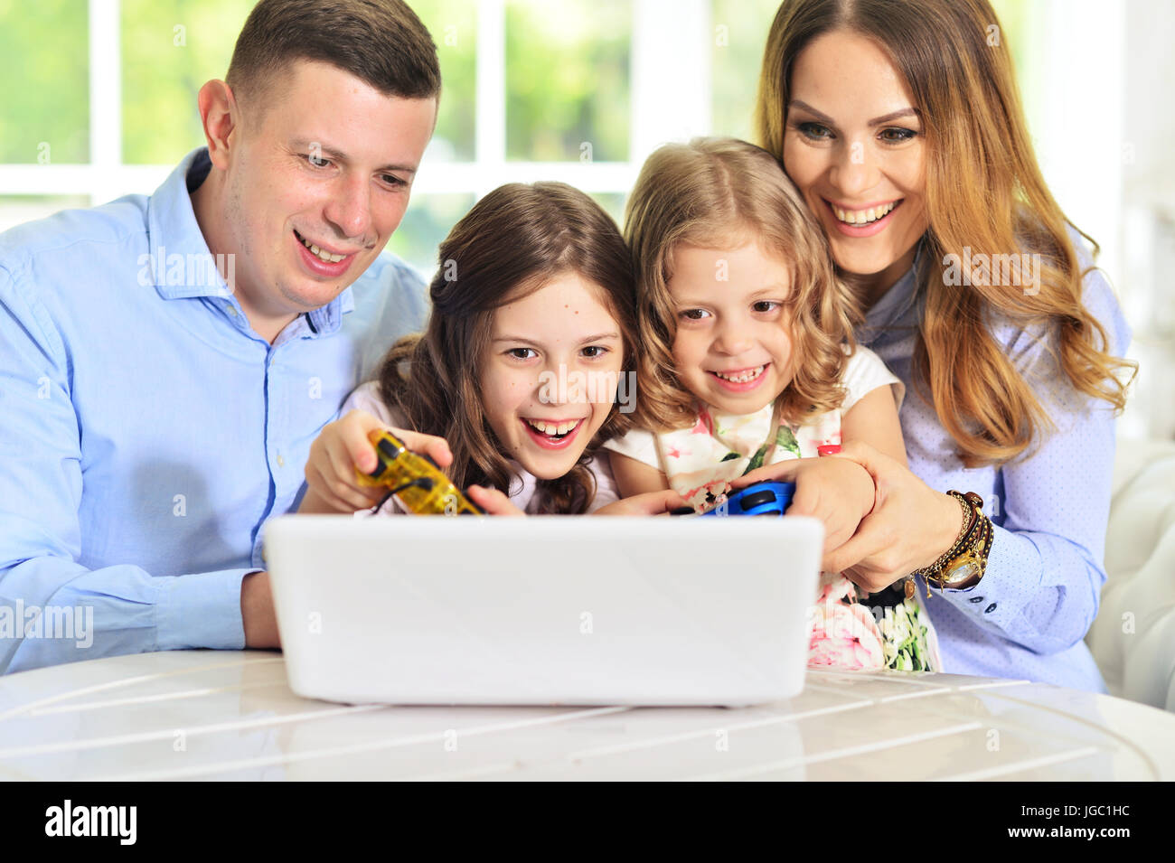 Famiglia giocando su laptop a tavola Foto Stock