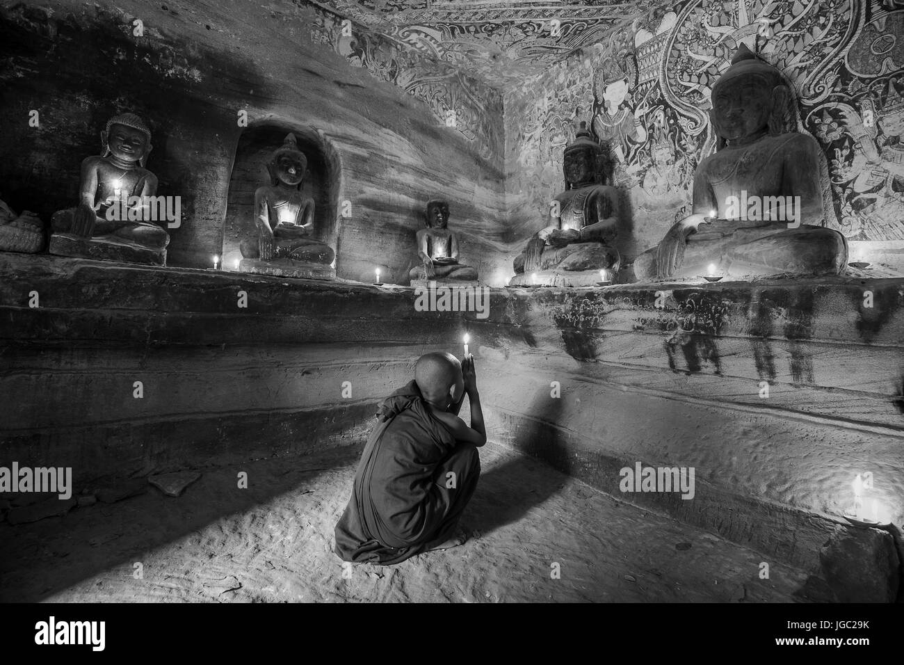 Monaco pregando con la luce di una candela in corrispondenza di Po Win Taung / grotta Hpowindaung - Monywa - Sagaing - Regione Nord del Myanmar Foto Stock
