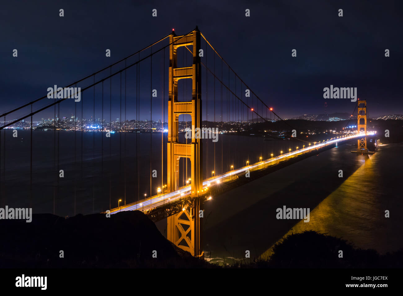 Golden Gate Bridge di notte con lo skyline di San Francisco in background Foto Stock