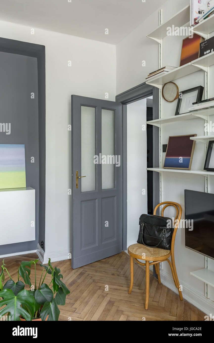 Grigio e bianco appartamento con libreria, poltrona e televisore Foto Stock