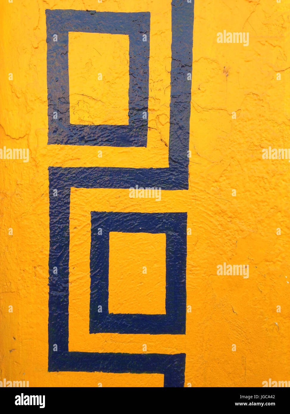 Colorato di giallo luminoso e blu modello geometrico dipinto sul muro di un edificio in una vista ravvicinata della superficie Foto Stock