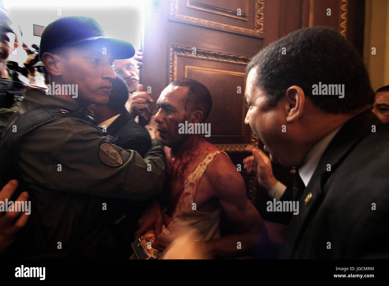 Caracas, Venezuela. 5 Luglio, 2017. Un uomo di sanguinamento è trattenuto dalle forze di sicurezza presso il Parlamento europeo a Caracas, Venezuela, 5 luglio 2017. Un gruppo di uomini violenti avevano addebitato al parlamento, il quale è controllato dall'opposizione. Secondo testimoni oculari, il gruppo di attaccanti erano i sostenitori del presidente socialista Maduro. Almeno tre membri dell'Assemblea nazionale sono stati feriti. Foto: Rafael Hernández/dpa/Alamy Live News Foto Stock