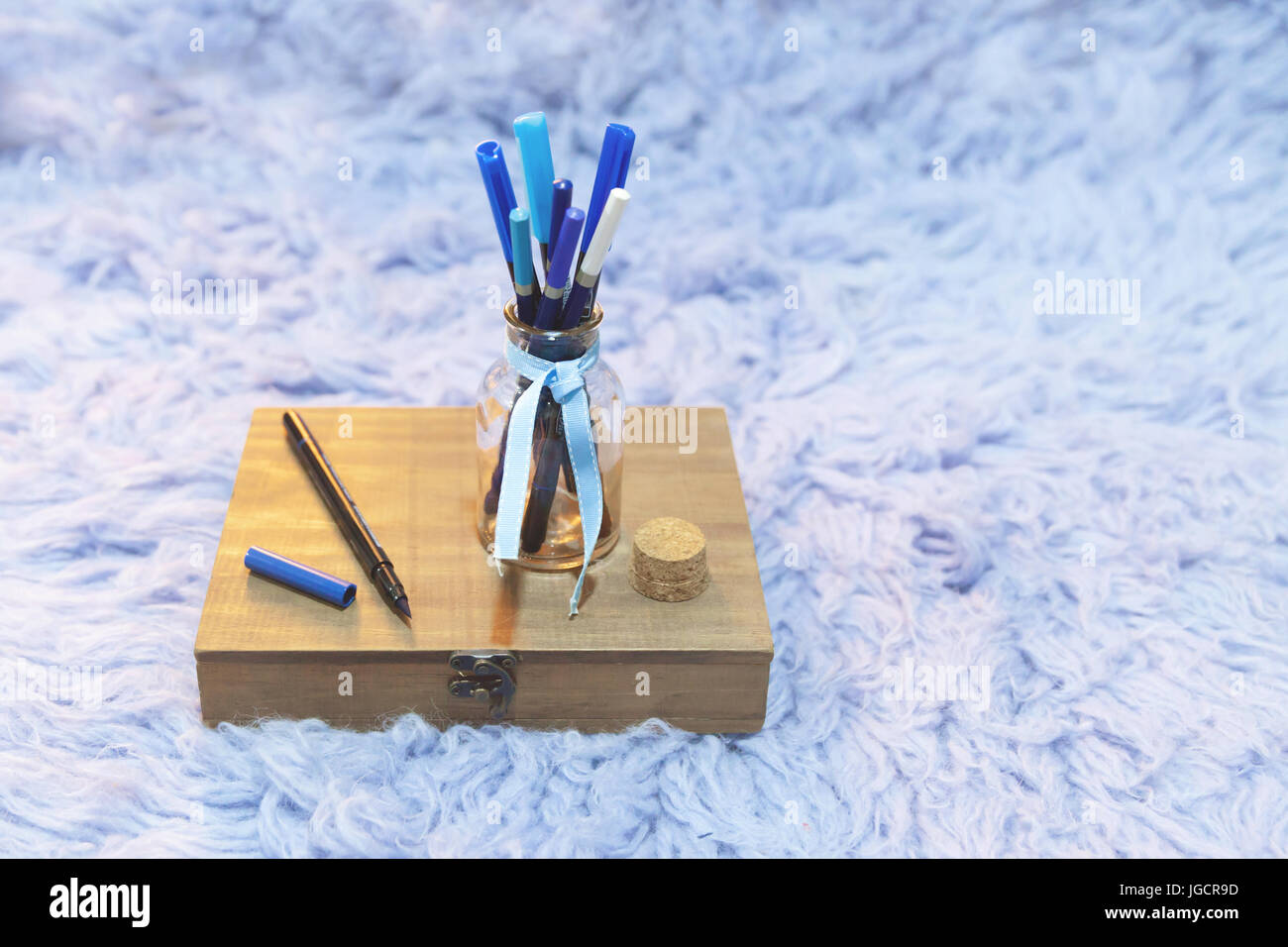 Scatola di legno e un vaso di vetro riempito con penne blu Foto Stock