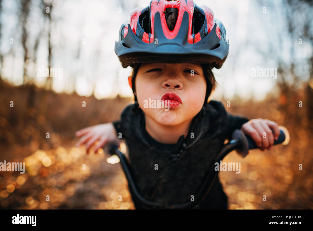 Ragazzo su una bicicletta che indossa un casco il raggrinzimento delle labbra Foto Stock